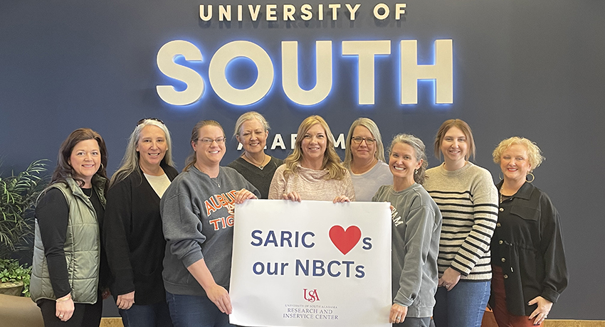 Nine current NBCTs holding a sign that reads SARIC heart emoji s our NBCTs with the SARIC logo below the words