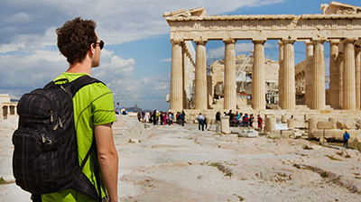 Student with backpack on looking at ruins.