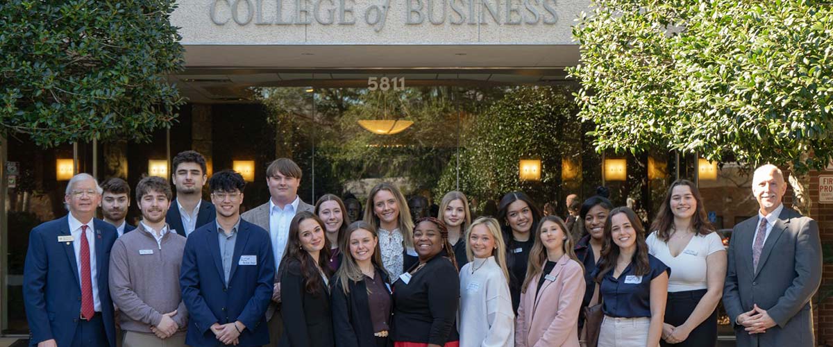 Image shows group of real estate students in front of the Mitchell College of Business exterior