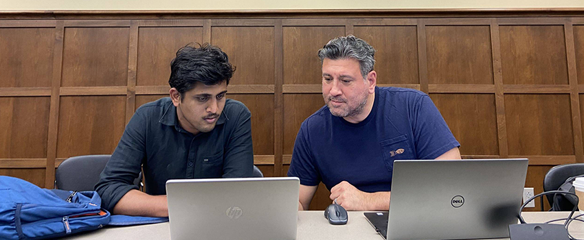 Two students looking into a computer screen in a classroom