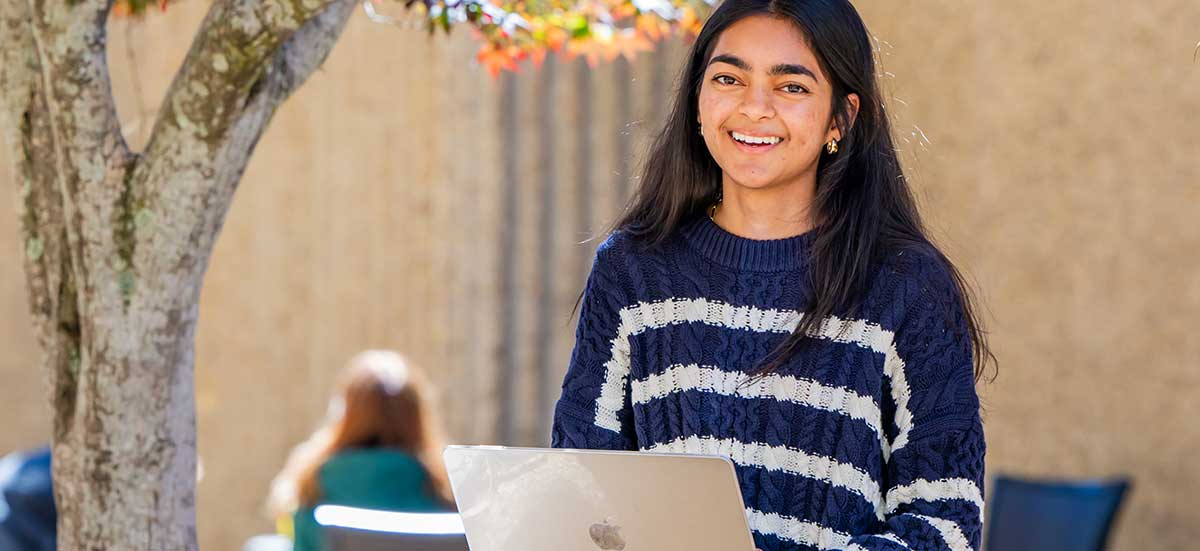 Student outside working on laptop.