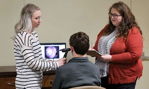 Students looking in a childs ear