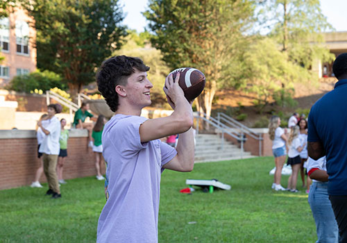 student throwing football