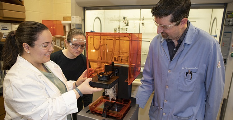 Senior chemistry students Madison McBroom, left, of Huntsville and Amanda Tanner of Cantonment, Fla., listen as Dr. William Reichert talks about their research with ionic liquids in the field of 3D printing. data-lightbox='featured'