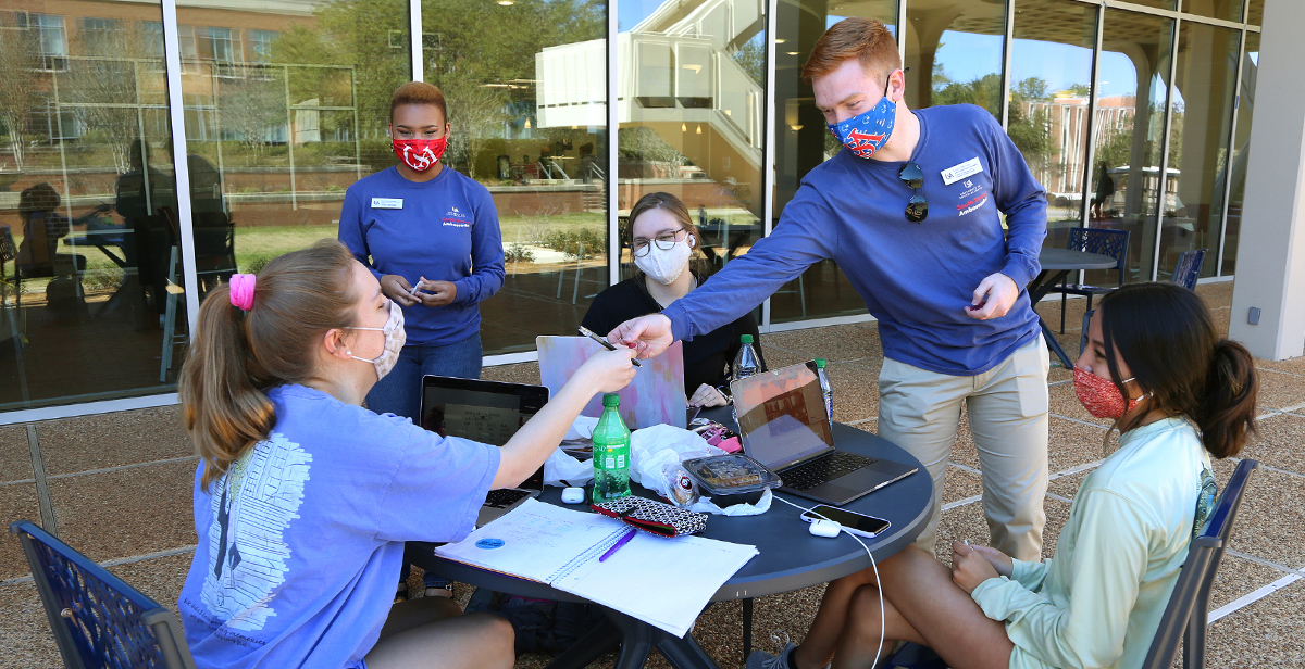 Grant Skinner and Sarai Garraway, both juniors and South Strong Ambassadors at the University of South Alabama, meet with fellow students outside the Student Center to talk about the importance of following precautions to keep people safe from COVID-19. data-lightbox='featured'
