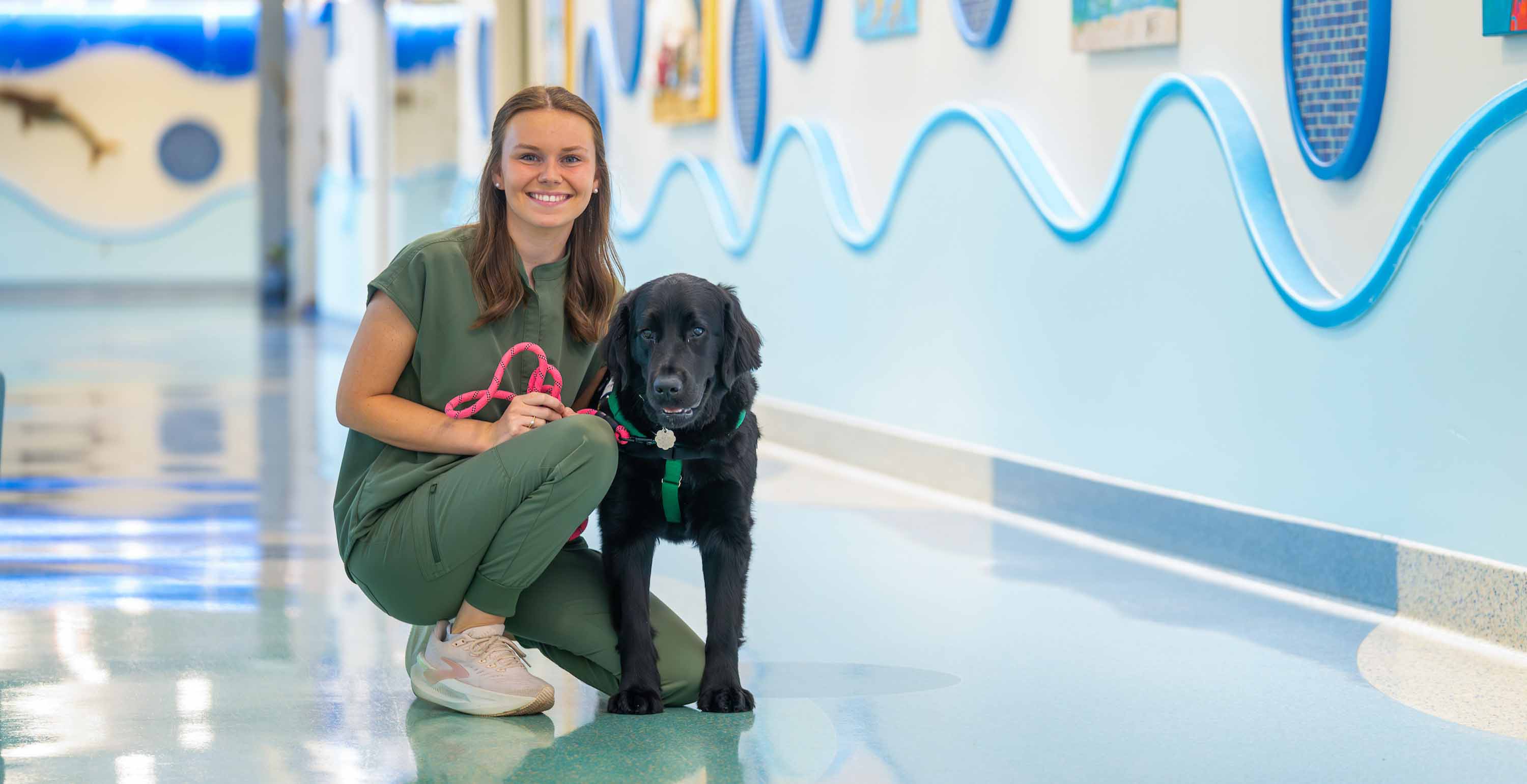 As the primary handler for USA Health Children’s & Women’s Hospital’s first full-time facility dog, Rainier, South graduate Emma Bryson combines recreational therapy with the healing power of a remarkable partner. Photo is of Emma and Rainier at the hospital. data-lightbox='featured'